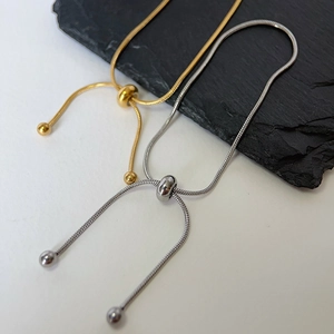 Detail of adjustable gold and silver snake chains with sliding bead clasp and metal balls