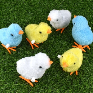 Detail of six colorful clockwork plush chicks on a green lawn for children's gift ideas