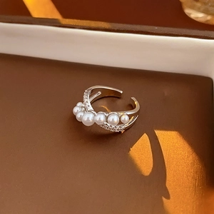 Macro detail of a silver crossover ring with pearls and zircons in a jewelry box