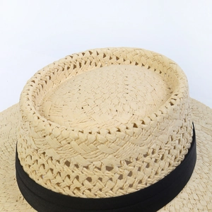 Detailed close-up of woven paper straw hat with black ribbon and fine texture