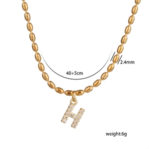 Detailed view of gold beaded chain and H letter pendant with sparkling zircon stones