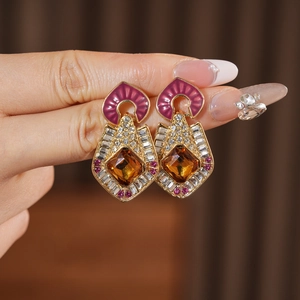 Close-up of vintage gold earrings with red enamel and amber stone inlay detailing