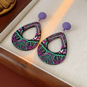 Détail de boucles d'oreilles bohèmes en goutte avec motifs géométriques dans un coffret bois