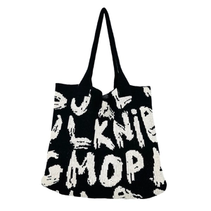 Close-up of knit tote bag showing black and white letter patterns and texture