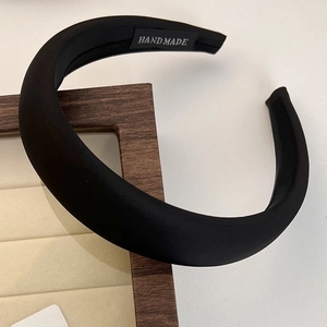 Detail showing handmade black headband texture and woven label on a jewelry display tray