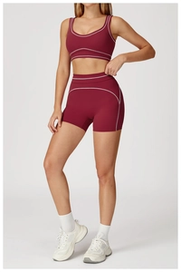 Detail of high-waisted yoga shorts with white contrast stitching in dark red stretch fabric