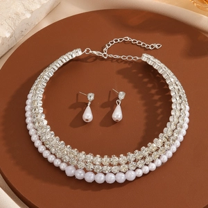 Elegant multi-layer pearl and rhinestone necklace with teardrop earrings on tray