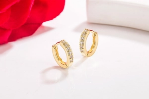 Close-up of golden small hoop earrings with paved cubic zirconia on white background