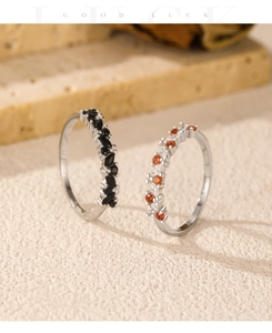 Close-up of stacked S925 silver rings with black, orange and white sparkling gemstones