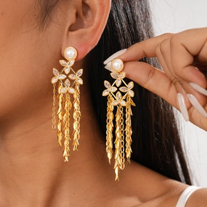 Model wearing gold flower earrings with pearl tassels and crystals in vintage court style