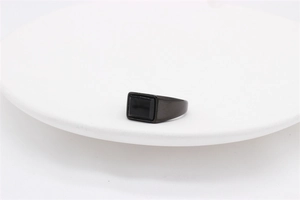 Macro shot of a black rectangle gemstone set in a wide smooth black stainless steel ring