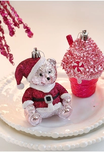 Close-up of pink glitter Christmas bear and cupcake ornaments on a white ceramic plate