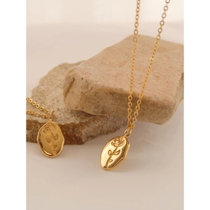 Detailed close-up of golden oval rose embossed pendants on a natural stone background