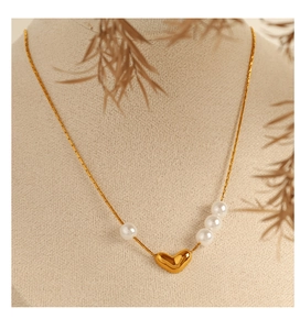 Gros plan d'un collier pendentif cœur doré orné de quatre perles blanches élégantes