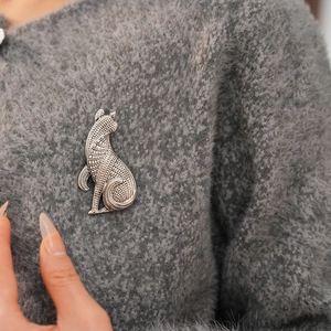 Detailaufnahme der Vintage-Katzenbrosche aus Silber mit Gravur auf einem grauen Pullover