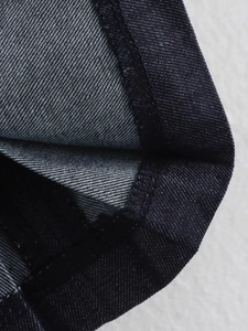 Dettaglio della gonna a pieghe in denim blu scuro con trama saia e cuciture