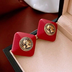 Detail of red faux leather diamond earrings with gold Alexander Magnus coin relief