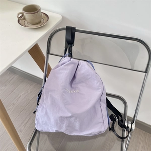 Detail eines lila Kordelzug-Rucksacks mit Nylon-Knitteroptik und weißem Stickerei-Logo
