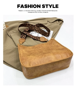 Detail of brown textured tote bag with leopard print strap on khaki blazer