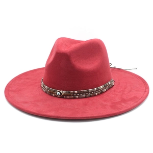 Detail of red fedora hat featuring ethnic ribbon and evil eye metal pendant accessory