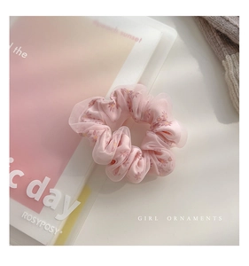 Dettaglio dell'elastico scrunchie in rete rosa con stampe floreali gialle delicate