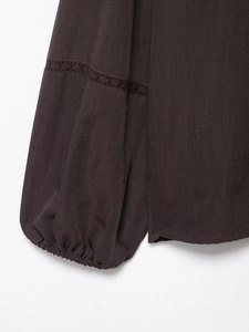 Détail du poignet d'une chemise marron foncé avec plis élastiques et dentelle ajourée