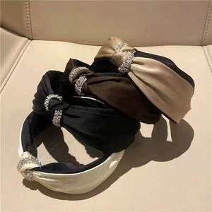 Detail of luxury satin knot headbands with shimmering rhinestone accents and silky finish