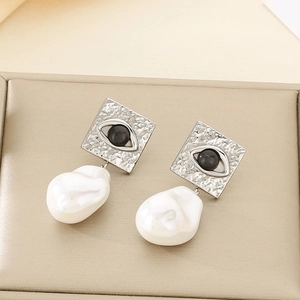 Detail of square silver earring with evil eye motif and baroque pearl drop