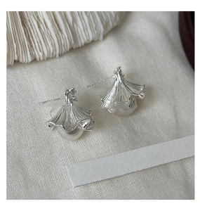 Macro shot of silver ginkgo leaf earrings with pearls and ruffled metal texture