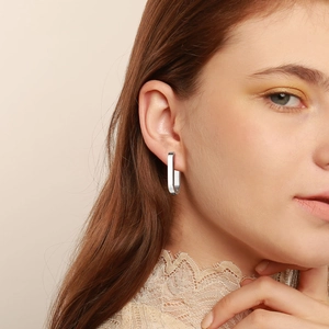 Close-up of elegant rectangular stainless steel hoop earrings on model for modern style