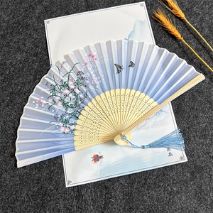 Detail of light blue silk folding fan with floral patterns and carved bamboo ribs
