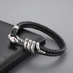 Macro detail of men's black braided leather bracelet with silver snake head clasp