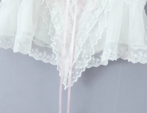 Detail eines weißen Netztops mit Spitzenstickerei und hellrosa Schleife für Damen