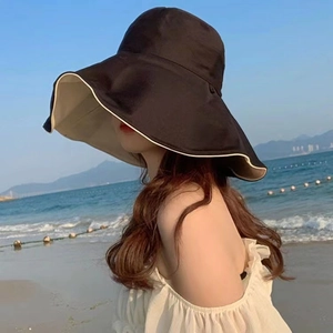 Detail of wide brim sun hat with black exterior and beige lining at the sunny beach