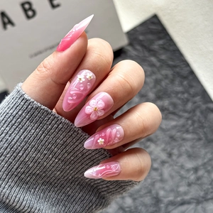 Macro detail of 3D white floral almond press-on nails with delicate pink gradient finish