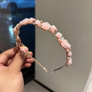 Detail of gold headband with pink resin roses, white pearls and sparkling rhinestones