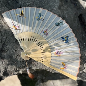 Traditional Suzhou embroidery folding fan with silk butterfly patterns on a bamboo frame