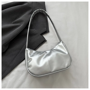 Close-up of metallic silver underarm bag on white fabric with a stylish grey blazer