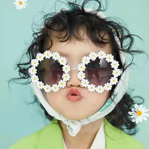 Toddler girl wearing cute daisy flower sunglasses with white petals and dark lenses