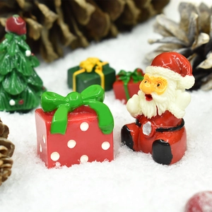 Miniature Santa Claus and red polka dot gift box figurines in artificial snow scene