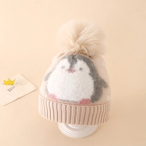 Close-up of knit texture and plush pompom on a penguin pattern winter hat for kids