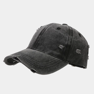 Dettaglio del cappello da baseball in cotone grigio usurato con strappi sulla visiera