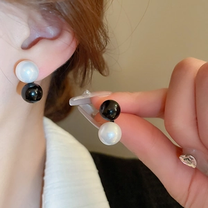 Elegant geometric black and white pearl earrings on model showing minimalist style