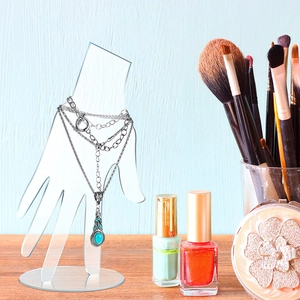 Transparent acrylic hand-shaped jewelry display stand with a necklace on a wooden desk