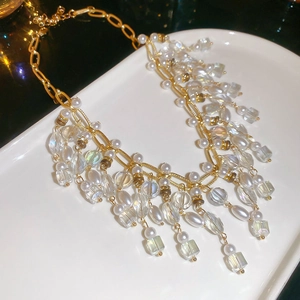 Close-up of pearl and crystal tassel necklace on a white ceramic tray with gold accents