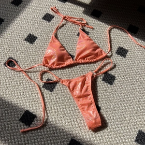 Macro detail of sparkly coral orange bikini fabric with glitter coating and metal ring link