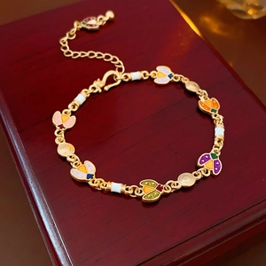 Gros plan d'un bracelet vintage doré avec breloques insectes en émail coloré et perles