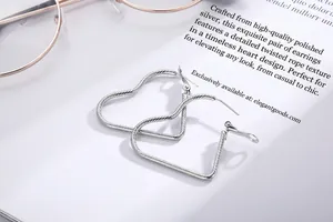 Macro shot of silver heart hoop earrings with spiral texture on a white book page