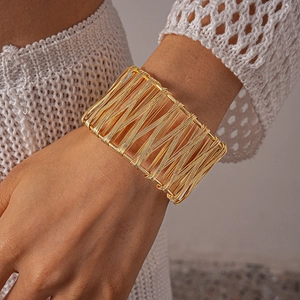 Detail of wide hollow geometric gold metal wire woven cuff bracelet worn on wrist