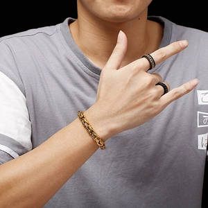 Men's gold Byzantine chain bracelet and black link rings on model hand